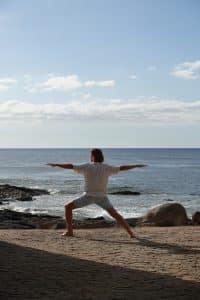 Mann macht Yoga mit Meer im Hintergrund