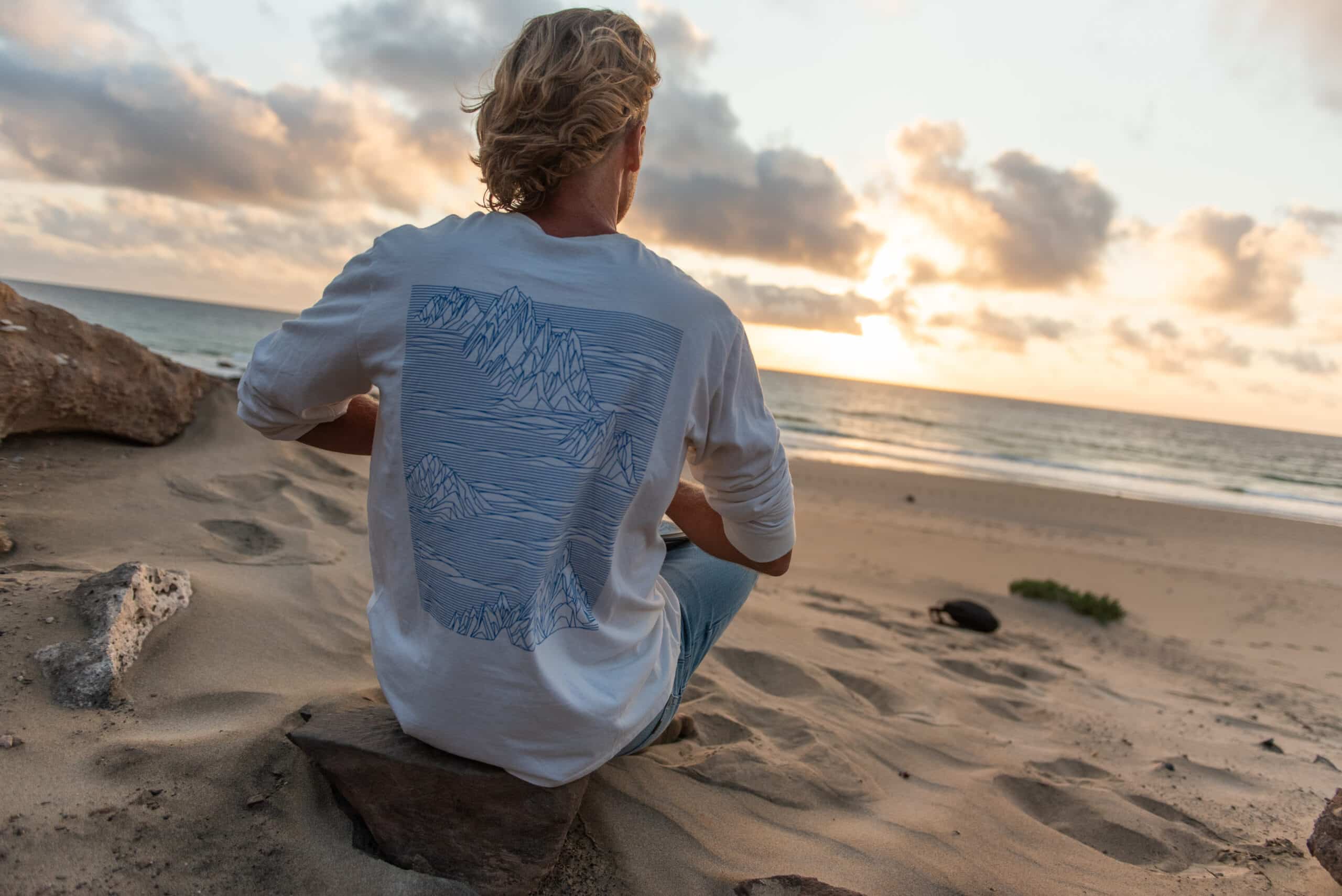 Andreas von NUANU sitzt mit dem Rücken zu uns am Strand